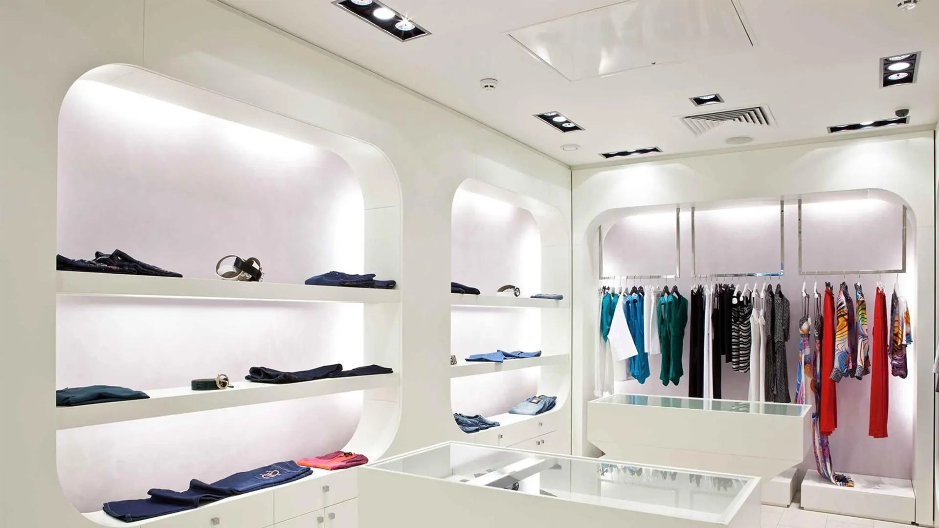 A white room with several shelves of clothes.