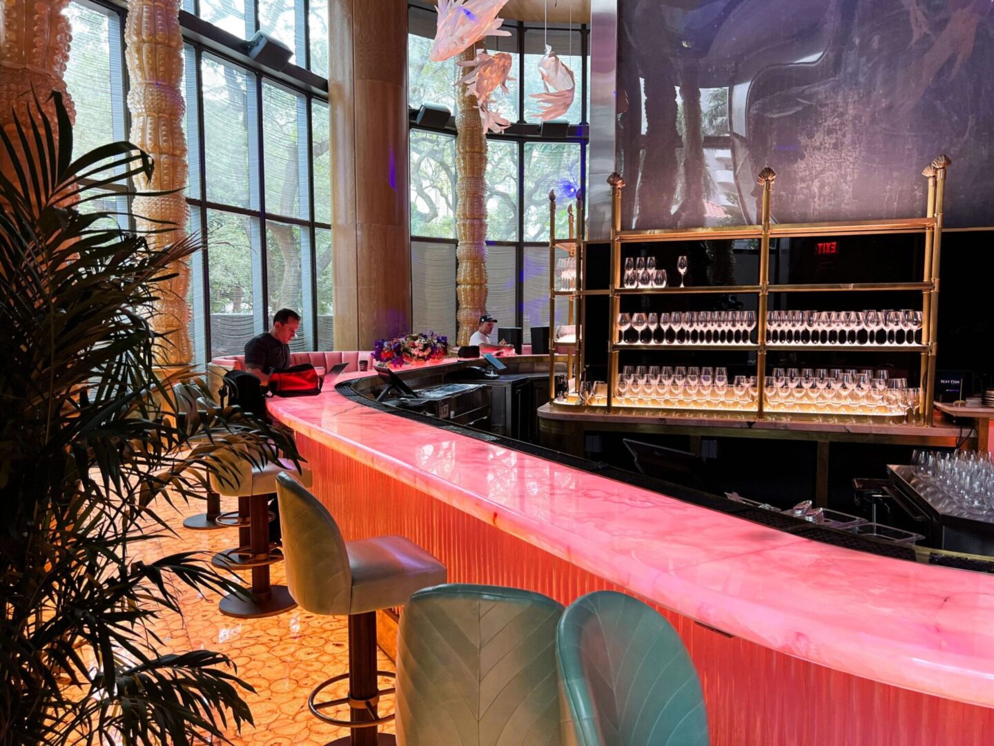 A bar with pink counter and chairs in front of a large window.