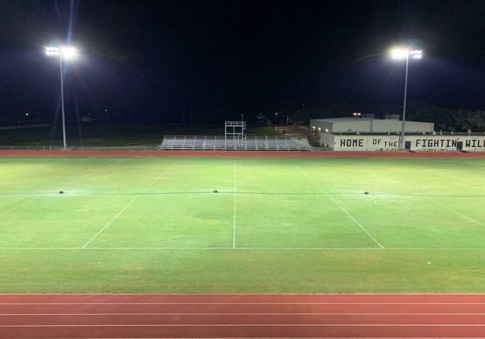 A field with lights on at night time.
