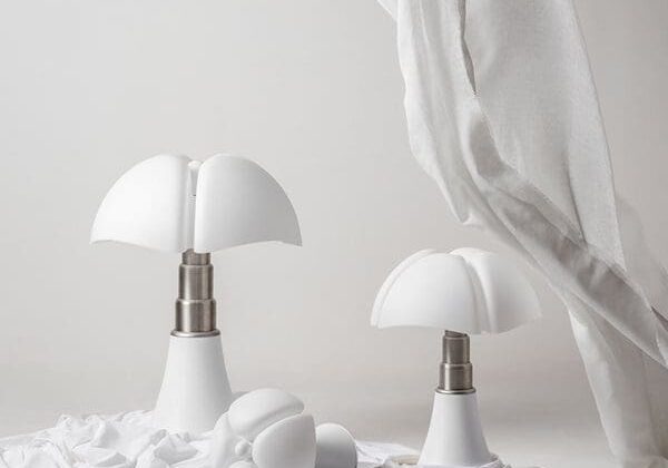 Minimalist white table lamps with soft lighting on a textured surface.